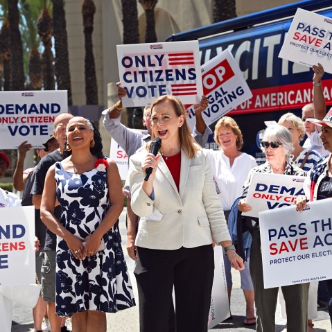 People hold signs saying "Only Citizens Vote" and "Pass the SAVE Act" outside.