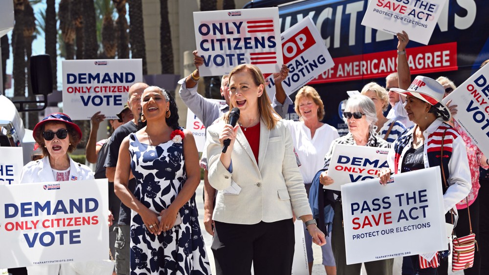 People hold signs saying "Only Citizens Vote" and "Pass the SAVE Act" outside.