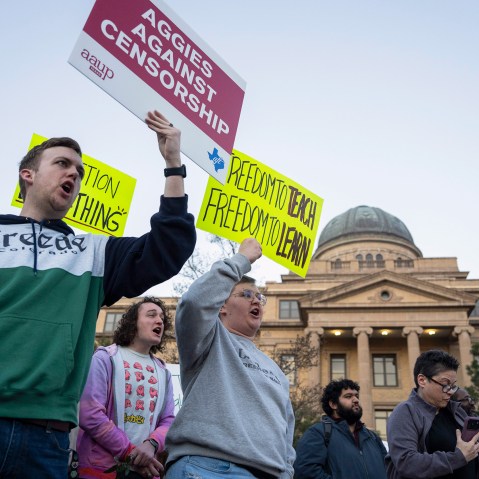 People hold signs calling for an end to censorship at Texas A&M's campus.