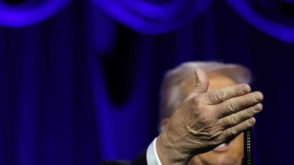 Donanld Trump's right hand obscures his face as he speaks at the National Prayer.