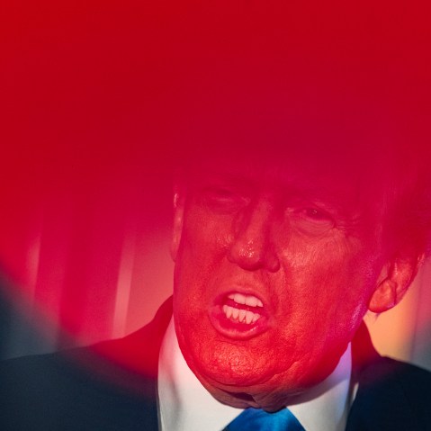 Top part of Donald Trump's face is seen through a round red light.