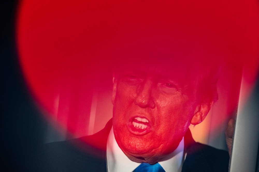 Top part of Donald Trump's face is seen through a round red light.