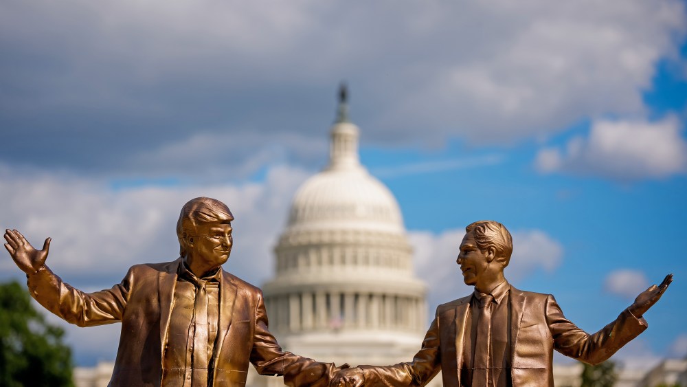 A golden statue depicts Donald Trump, left, and Jeffrey Epstein holding hands. In the background, the Capitol is out of focus.