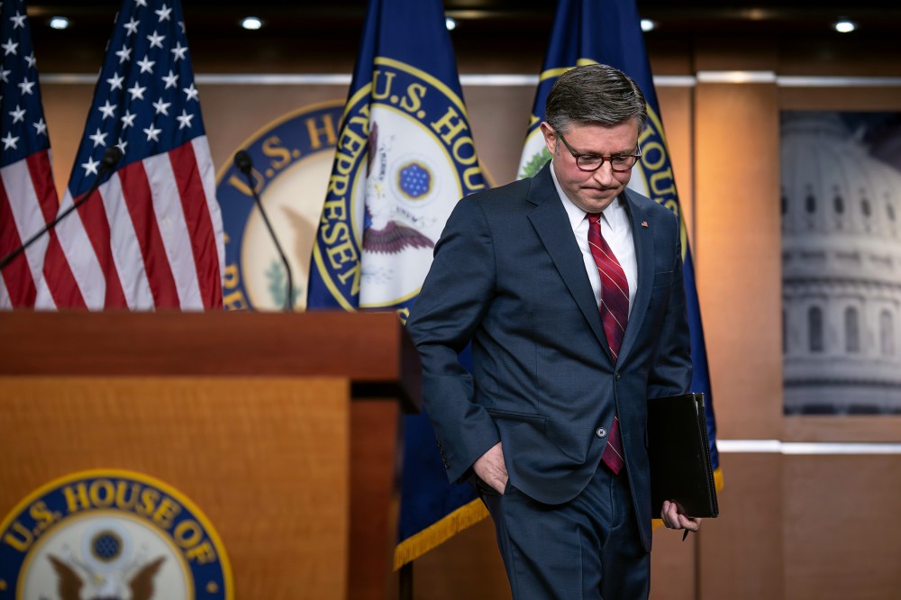 Mike Johnson walks up to a podium with his head down and hand in his pocket.