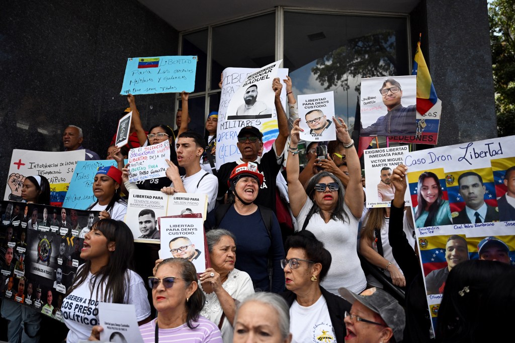 People hold up posters calling, in Spanish, for the freedom of political prisoners.