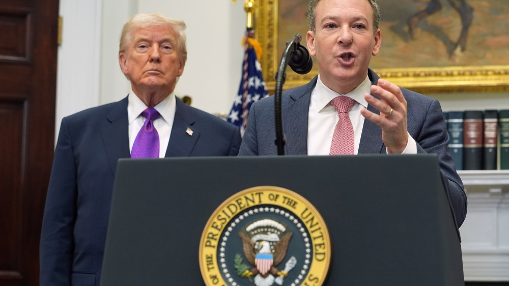 Donald Trump, left, and Lee Zeldin, who speaks into a microphone at a podium.
