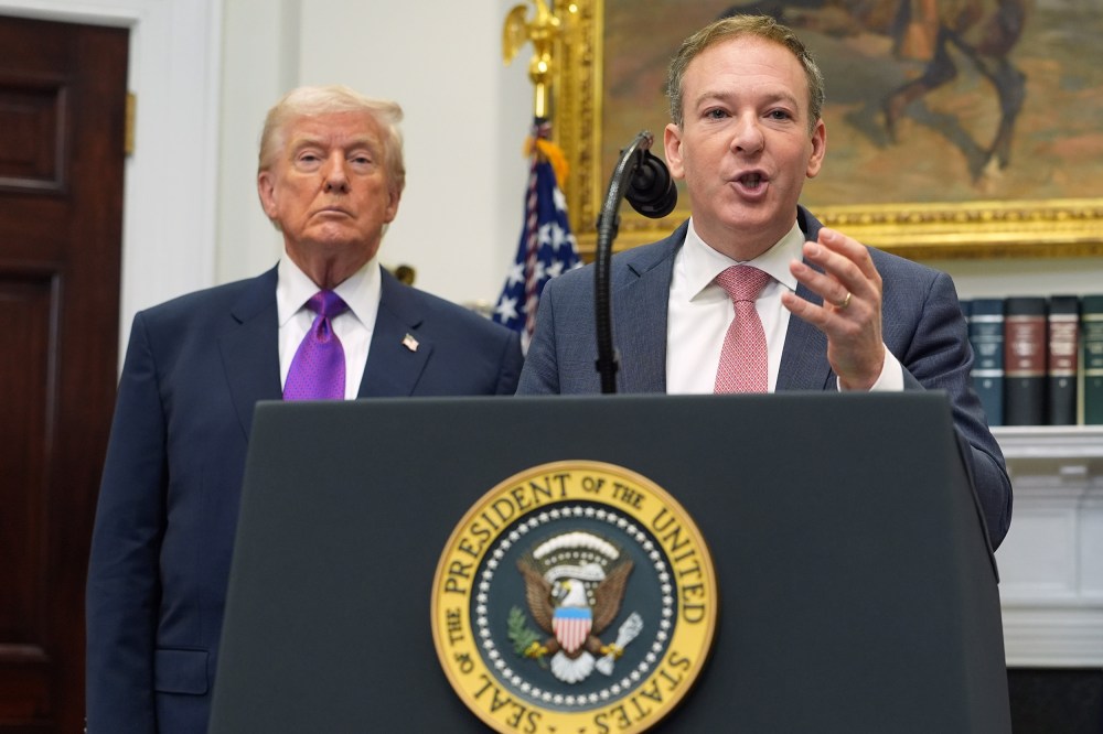Donald Trump, left, and Lee Zeldin, who speaks into a microphone at a podium.