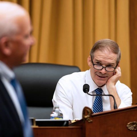 Jim Jordan, right, rests his head on his hand as he talks to a person turned away from the camera.