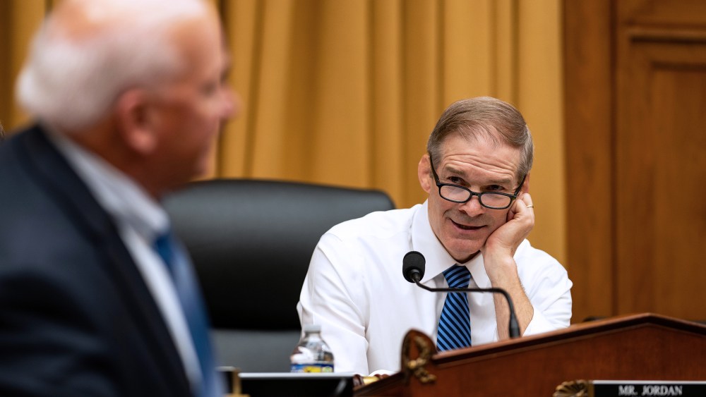 Jim Jordan, right, rests his head on his hand as he talks to a person turned away from the camera.