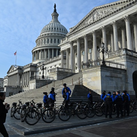 Police officers stand on the side of the Capitol building with their bikes.