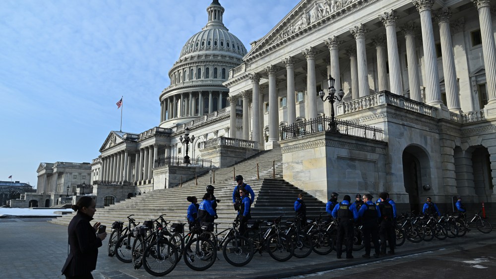Police officers stand on the side of the Capitol building with their bikes.