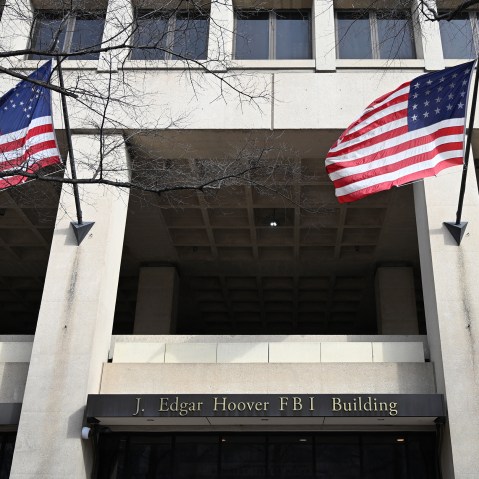 FBI headquarters sign is seen between two American flags.