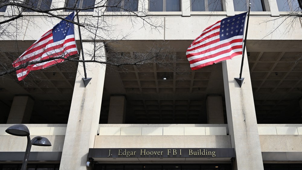 FBI headquarters sign is seen between two American flags.