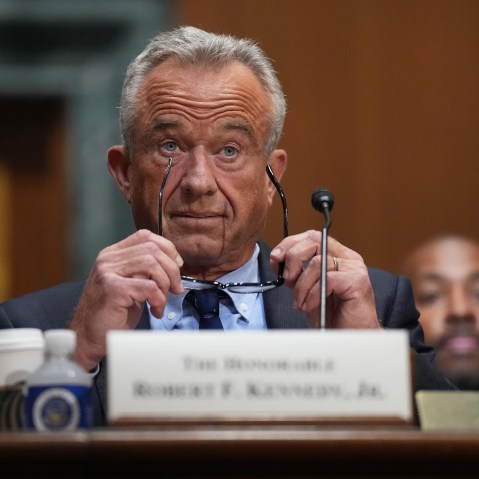 RFK Jr. raises his eyebrows with his glasses in his hands.