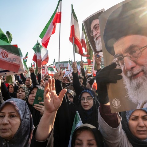 People wave Iranian flags and carry portraits of Ayatollah Ali Khamenei.