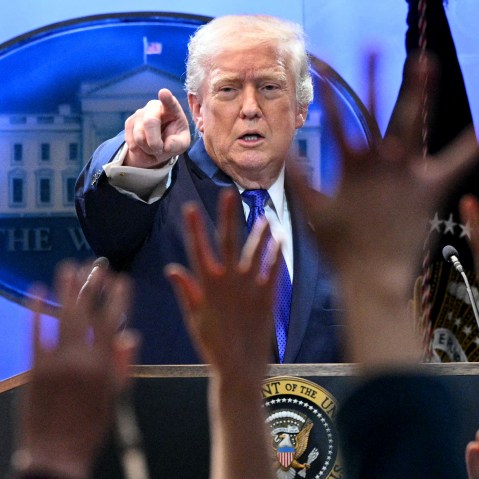 Donald Trump points at a press member as they raise their hands to ask questions.