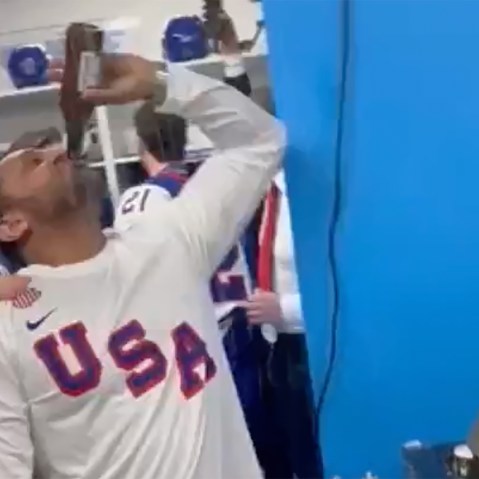 Kash Patel chugs a bottle of beer in front of hockey players.