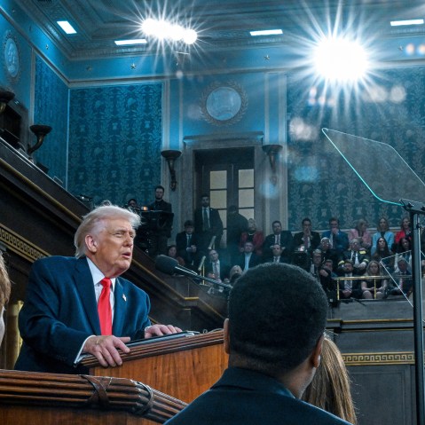 Bright lights shine on Donald Trump as he speaks at a podium.