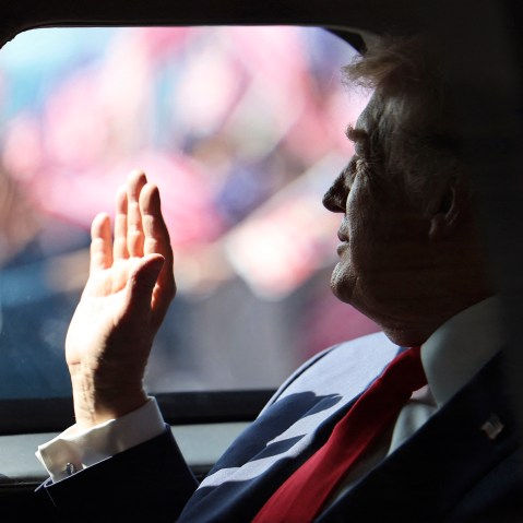 President Donald Trump waves from his official vehicle as he departs from Kuala Lumpur International Airport.