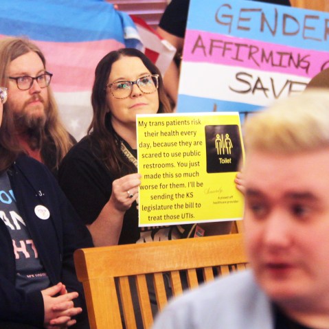 Several people hold up pro-transgender rights signs.