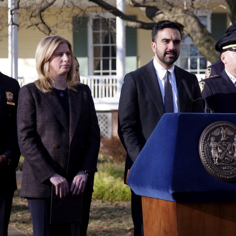 Zohran Mamdani stands at the podium along with members of NY law enforcement.