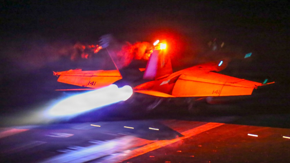 A fighter jet takes off at night.