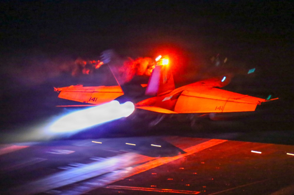 A fighter jet takes off at night.