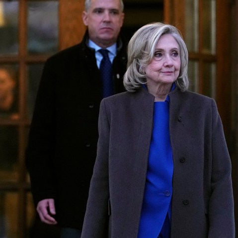 Hillary Clinton, right, looks off while walking out from a double set of doors.
