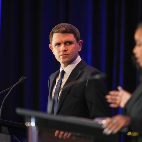 James Talarico, in focus, left, looks at Jasmine Crockett, out of focus, right, as she speaks. Both stand at podiums with microphones.