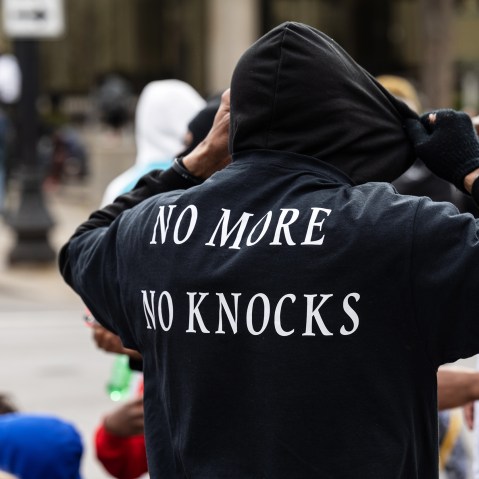 a person is seen from behind as he adjusts his black hoodie.