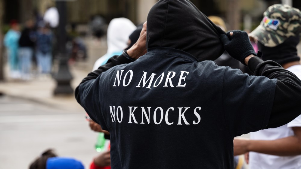 a person is seen from behind as he adjusts his black hoodie.