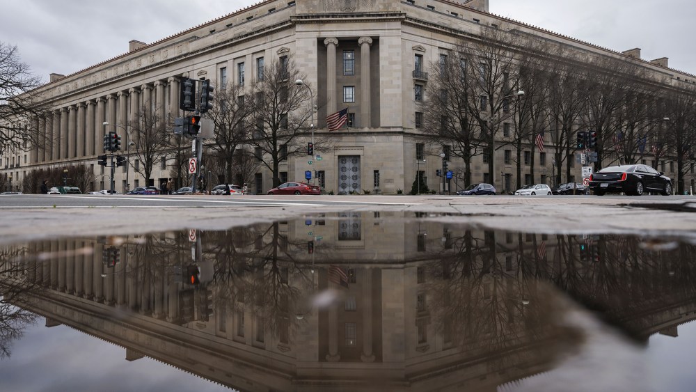 The Department of Justice building, seen reflected in a puddle.