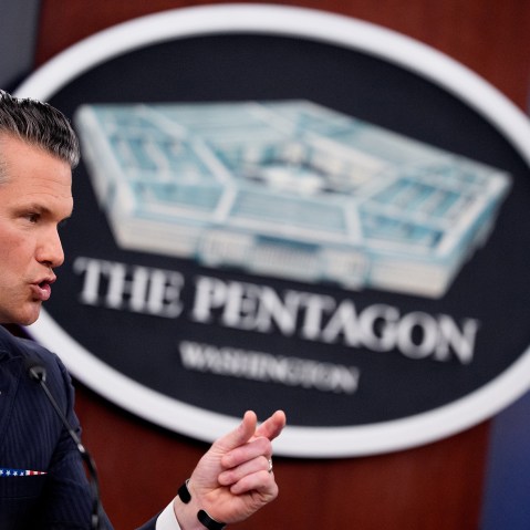 Pete Hegseth speaks in front of a sign for the Pentagon.