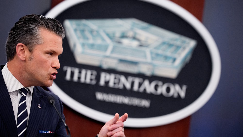 Pete Hegseth speaks in front of a sign for the Pentagon.