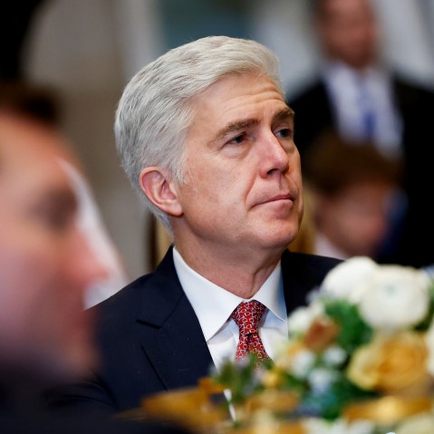Neil Gorsuch looks on as he sits at a table with other people.