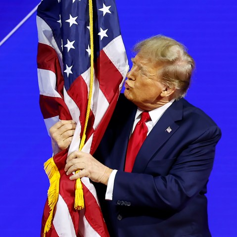 President Donald Trump hugs an American flag.