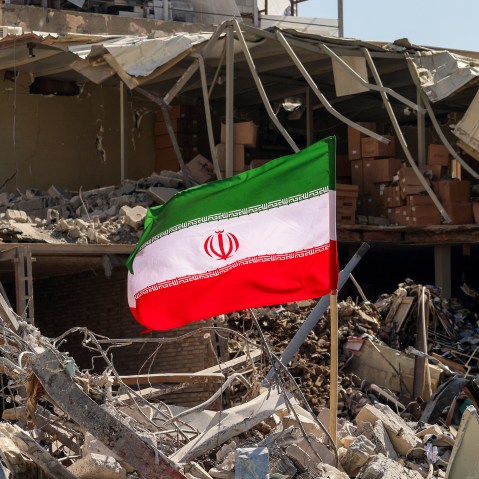 An Iranian flag is placed amids rubble and debris next to a destroyed residential building in Tehran.