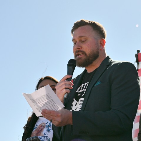 Sky Roberts reading off a paper, holding a mic during a protest against Jeffrey Epstein.