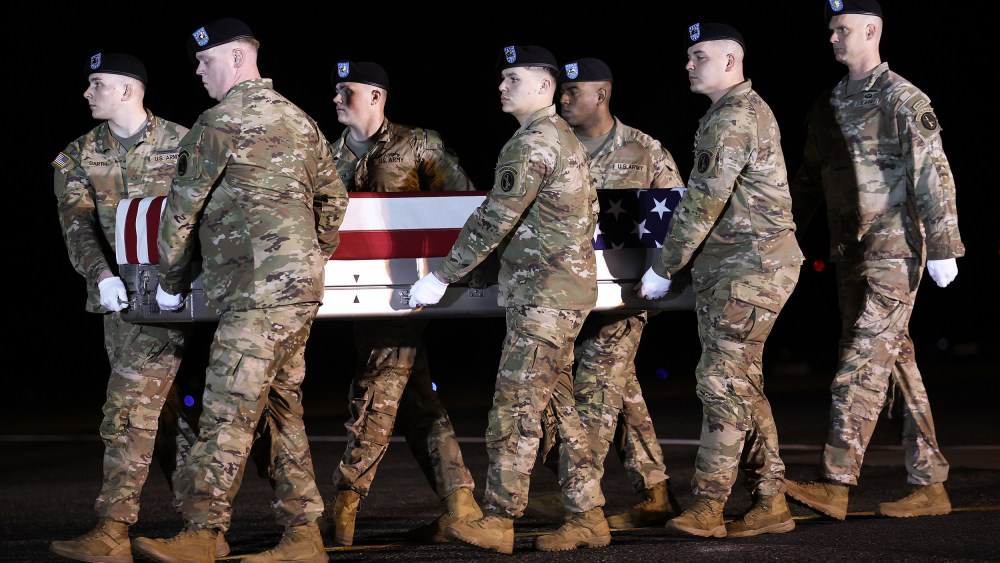 A U.S. Army carry team moves a flag-draped transfer case containing the remains of Maj. Sorffly Davius, 46, at Dover Air Force Base.