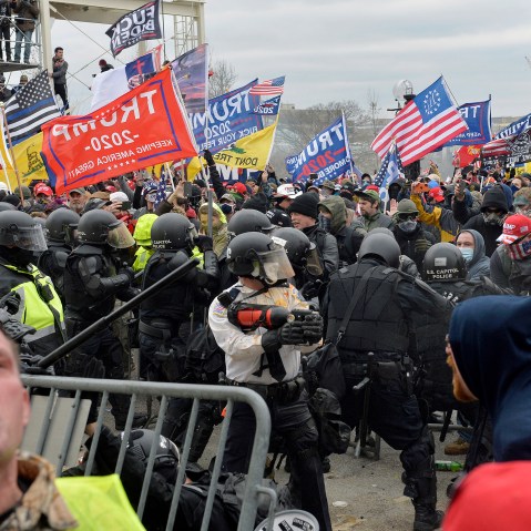 A man seen screaming in the foreground as other protestors clash with law enforcement.