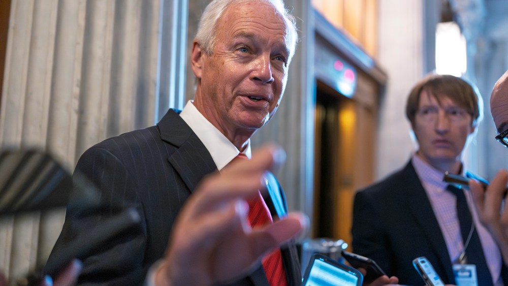 Ron Johnson surrounded by people holding their phones out to him.