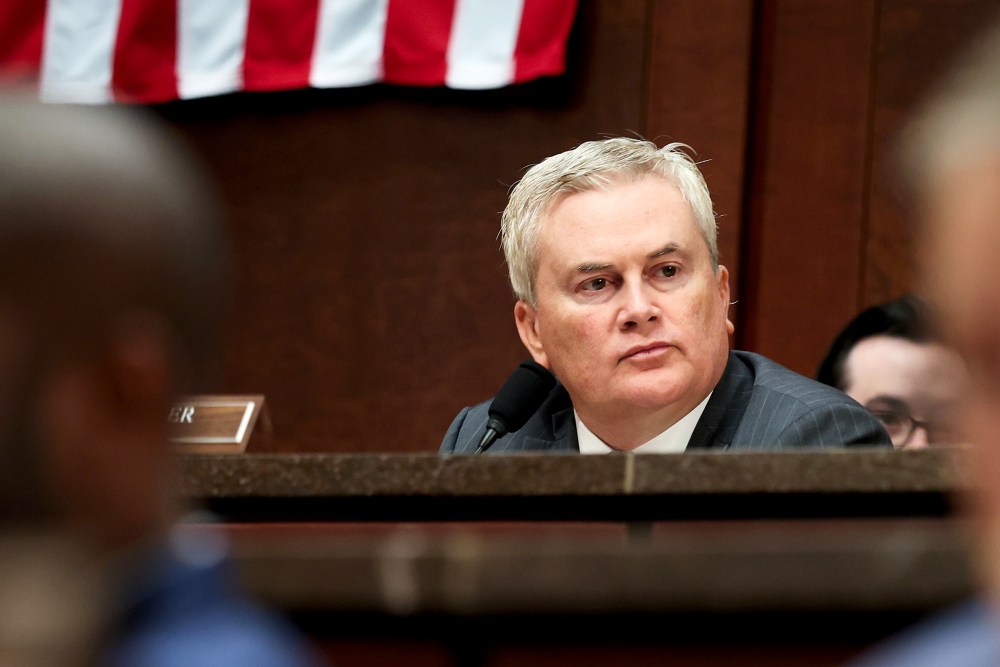 James Comer sits behind other members of the congress in front of an American flag.