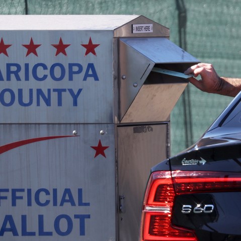 A voter drops their ballot into a drop box outside of the Maricopa County Tabulation and Election Center in Phoenix.