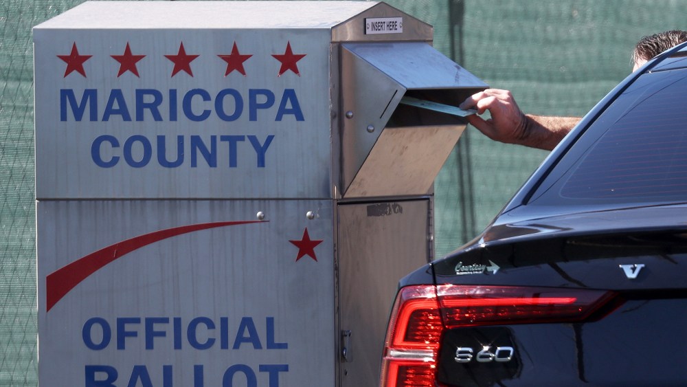 A voter drops their ballot into a drop box outside of the Maricopa County Tabulation and Election Center in Phoenix.