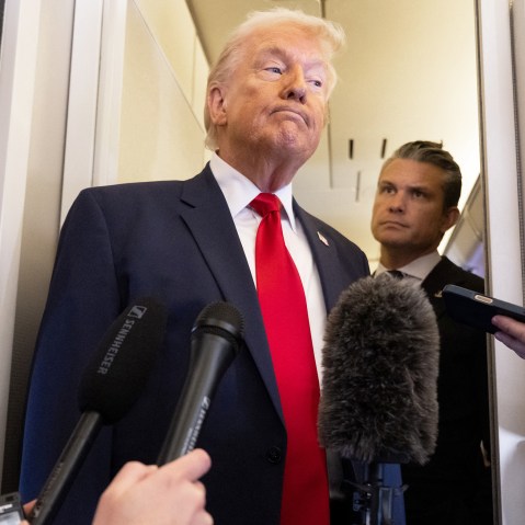 President Donald Trump speaks with the media as Defense Secretary Pete Hegseth looks on aboard Air Force One.
