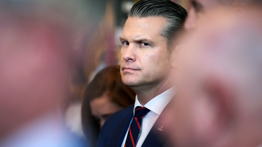 Pege Hegseth’s profile can be seen among other people who are out of focus.