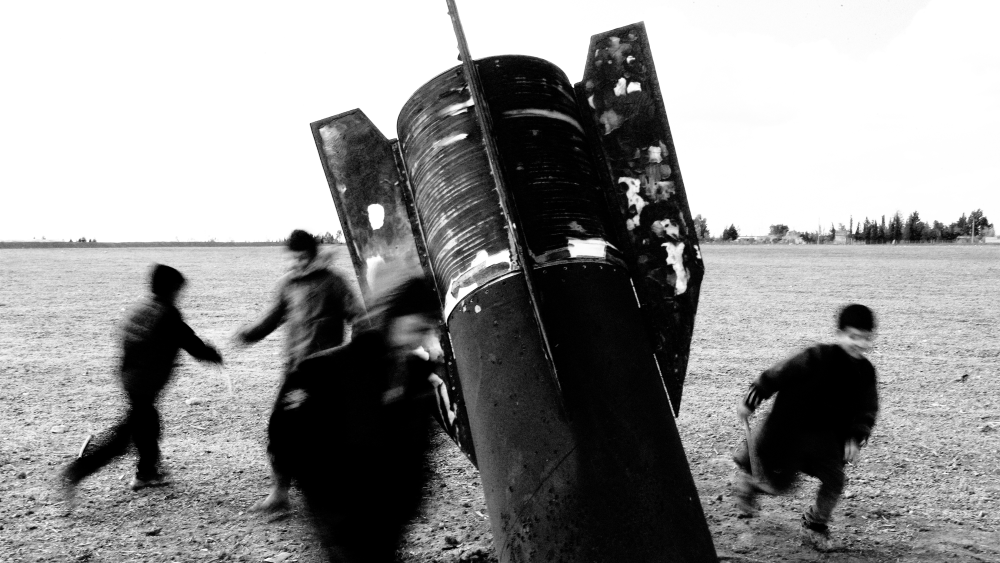 Children play around an unexploded missile that landed in an open field on the outskirts of Qamishli, eastern Syria, on March 5, 2026